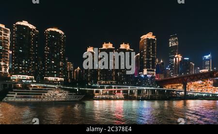 Chongqing, Chine - août 2019 : vue nocturne sur la ville de Chongqing illuminée sur la rivière Jialing et Yangtze avec bateau de luxe à passagers de croisière amarré sur le TH Banque D'Images