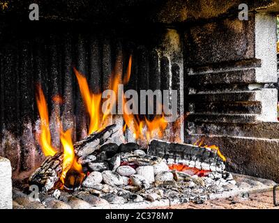 Bois de chauffage accumulé pour un barbecue dans un barbecue en béton - bois brûlé et charbon ajouté Banque D'Images