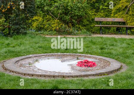 Gros plan de la colombe de la paix sculptée dans le sol avec une couronne du jour du souvenir à côté. Pinner Memorial Park, Pinner, NW London Banque D'Images