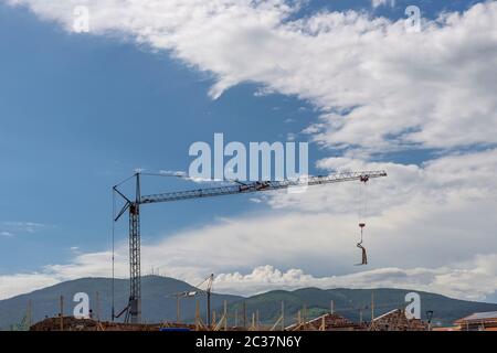 Une grue mobile avec des équipements accrochés à une extrémité se déplace sur un chantier de construction avec la montagne de Monte Serra en arrière-plan, Bientina, Pise, Italie Banque D'Images