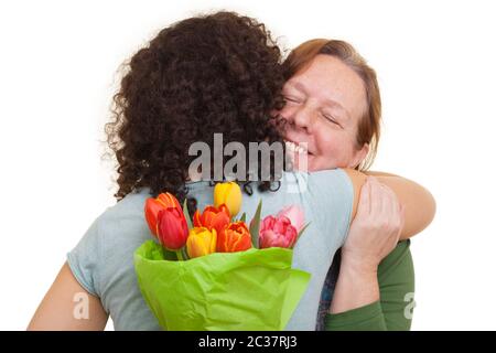 Jeune femme avec des tulipes cachées derrière son dos embrassant la femme âgée, isolée sur fond blanc. Fête des mères, Saint-Valentin, Banque D'Images