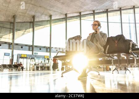 Femme assise au terminal de l'aéroport sur l'annulation de vol, appelant la famille, assis dans presque vide terminal de l'aéroport en raison de la pandémie de coronavirus, Covid Banque D'Images