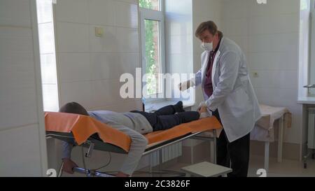 Le médecin traite les patients. Le chirurgien effectue une opération pour éliminer la plaie de maïs sur la jambe du patient. Hôpital de la ville. Mai 2020, Brovary, Ukraine Banque D'Images