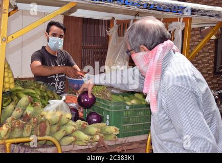 Port de masque un client indien et vendeur de légumes en maintenant social distancer et tout en achetant et en vendant des légumes pour la prévention corona Banque D'Images