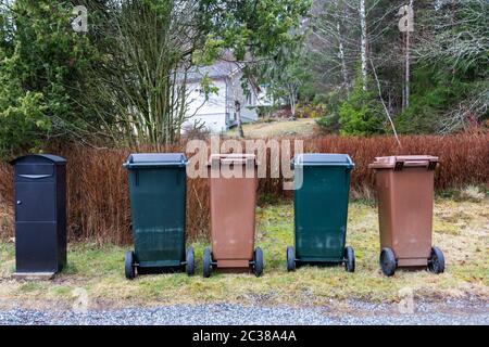 Vue des conteneurs à ordures bruns et verts typiques pour le tri des ordures organiques et non organiques près de la boîte postale noire . Concept d'environnement, standard Banque D'Images