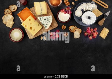 Modèle de conception d'assortiment de fromages. Fromage bleu, fromage doux, vin, raisin, tiré du dessus sur fond noir avec Copy spa Banque D'Images