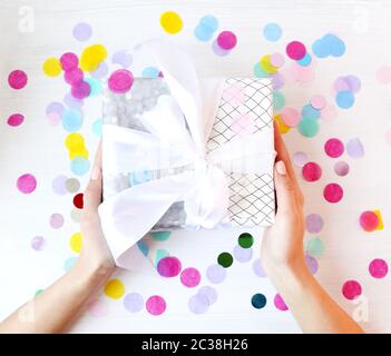 Petit femme portant une boîte cadeau sur des confettis Banque D'Images