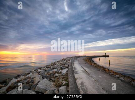 Quai Rocky à l'entrée du port de Mrzezyno au coucher du soleil, Pologne. Banque D'Images