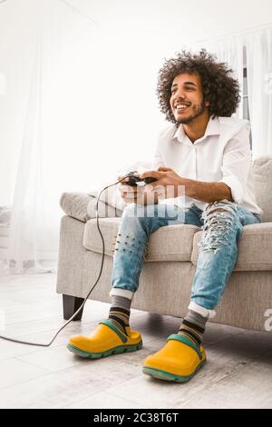 Drôle d'homme aime jouer à un jeu d'ordinateur. Jeune joueur souriant s'amuser en appuyant sur les boutons du joystick. Concept de divertissement. Image teintée Banque D'Images