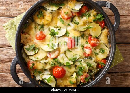 Délicieux gratin de courgettes avec fromage et tomates cerises dans une casserole sur la table. Vue horizontale du dessus Banque D'Images