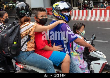 Famille de quatre personnes avec masque facial sur moto pendant la pandémie Covid 19, Bangkok, Thaïlande Banque D'Images