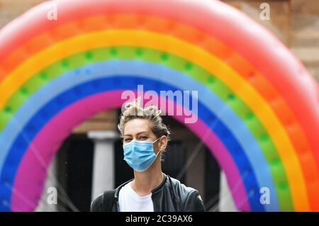 Une femme portant un masque facial passe devant un grand arc-en-ciel à Covent Garden, Londres, après que les médecins en chef du Royaume-Uni aient accepté de réduire le niveau d'alerte du coronavirus de quatre à trois après une « maladie » et une diminution continue des cas dans les quatre pays. Banque D'Images