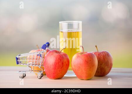 Les pommes et le jus de pomme avec un panier sur une table en bois, extérieur Banque D'Images