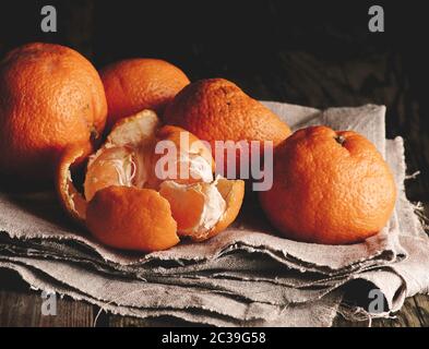 Tas de ronde non pelées mandarin orange mûre sur une serviette en lin gris, table en bois, clé faible Banque D'Images