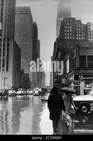 Entre les gratte-ciels de New York sur East 42nd Street (intersection 2nd Avenue) par temps pluvieux dans les années 1980. Dans l'arrière-plan à droite, se trouve le Chrysler Building. Sur la gauche en face se trouve le Daily News Building. Banque D'Images