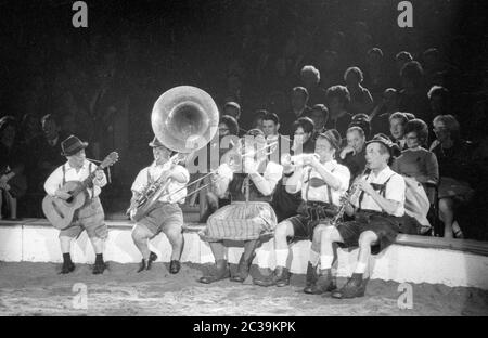 Un groupe de musique composé de clowns vêtus de costumes traditionnels bavarois au Circus Krone. Banque D'Images