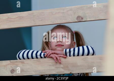 Romantique fille triste sur une rampe en bois regarde vers le haut et est triste. Banque D'Images