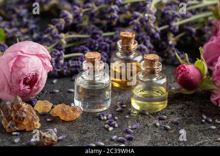 Bouteilles d'huile essentielle avec encens, roses et lavande Banque D'Images