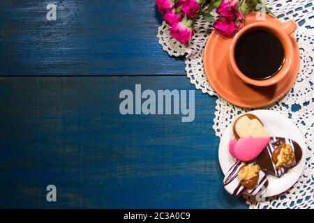 Fleurs romantique avec café et friandises sur la table Banque D'Images