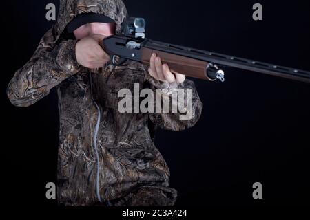 Hunter en vêtement de camouflage avec une arme à feu sur un fond noir isolé. L'homme avec le fusil. Jeune homme dans un costume de camouflage avec une arme à feu. Soldat, troupe Banque D'Images