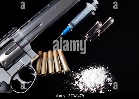 Une seringue avec une aiguille se trouve sur la table à côté de la drogue et les armes. Un pistolet à balles, seringue et les médicaments se trouvent sur le tableau noir. La vente, Banque D'Images