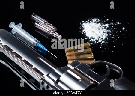 Une seringue avec une aiguille se trouve sur la table à côté de la drogue et les armes. Un pistolet à balles, seringue et les médicaments se trouvent sur le tableau noir. La vente, Banque D'Images