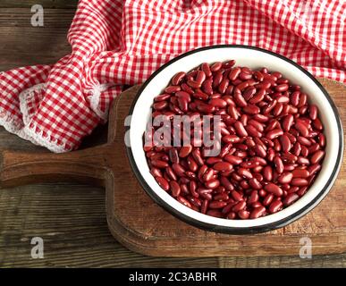 Ovale brut haricots rouges dans une assiette sur une table en bois. Repas biologiques. Aliments naturels sains végétariens. Banque D'Images