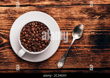 Les grains de café torréfiés tasse blanche en plus de surface en bois rustique Banque D'Images