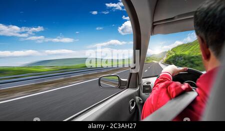 L'homme conduit une voiture sur une autoroute de banlieue. Banque D'Images