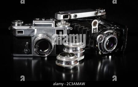 Deux vieux appareils photos et lentille sur un fond noir Banque D'Images