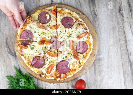 La main de la femme prend un morceau de pizza de la chandelle ronde en bois, a fourni l'espace pour le texte Banque D'Images