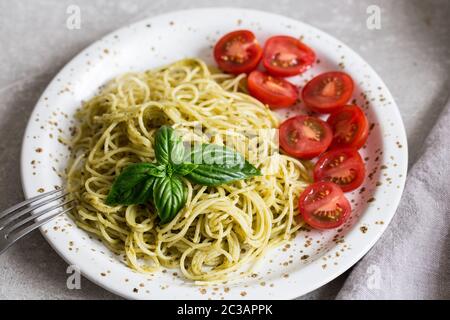 Spaghetti avec sauce pesto fait maison, les feuilles de basilic et les tomates Banque D'Images