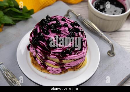 Les crêpes ont servi de la crème avec du fromage cottage et des bleuets sur un beau plateau en bois, à côté de la confiture de bleuets et de la menthe, un magnifique arrière-plan, vue sur le dessus Banque D'Images