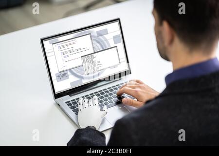 Homme avec prothèse de main travaillant sur ordinateur portable. Membre artificiel Banque D'Images