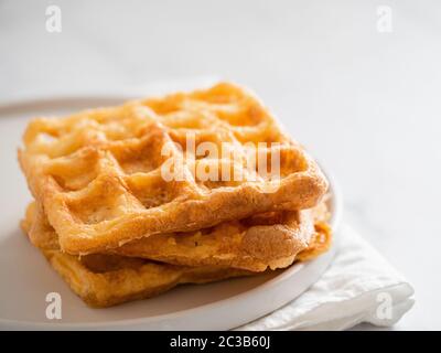 Gaufres salées parfait keto. Deux ingrédients chaffles sur plaque sur fond de marbre blanc. Les œufs et le fromage parmesan bas carb gaufres. Banque D'Images