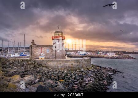 Phare de Howth avec mouettes volantes au beau coucher du soleil Banque D'Images