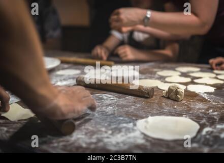 Broche à roulettes en bois et pâte plate portionnée qui sera utilisée pour la fabrication de boulettes chinoises traditionnelles pendant la cuisine dans un ho de voyageurs Banque D'Images