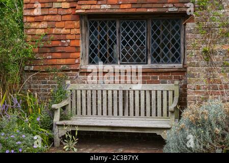 Fenêtre en forme de croix ornée de perles dans un mur de briques et de carreaux avec banquette sous. Sussex, Angleterre Banque D'Images