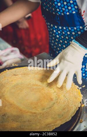 Femme faisant des crêpes salées aux œufs dans une petite boulangerie locale de rue de la ville de Yichang, en Chine Banque D'Images
