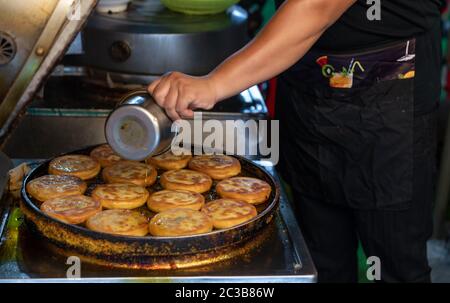 Homme faisant des crêpes à pain à partir de pâte de farine dans une petite boulangerie locale dans la rue dans le quartier musulman, ville de Xian, Chine Banque D'Images