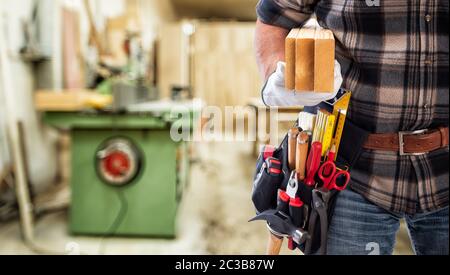Gros plan. Carpenter avec ses mains protégées par des gants porte les planches en bois. Industrie de la construction. Banque D'Images