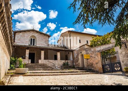 L'église de San Severino. Le porche, la fenêtre à meneaux, la croix, les murs médiévaux. À Spello, province de Pérouse, Ombrie, Italie. Banque D'Images