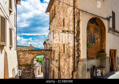 Une ruelle caractéristique du village médiéval, avec des maisons en pierre et en brique. Une niche avec une fresque de la Vierge Marie avec le bébé Jésus. Une fontaine. Banque D'Images