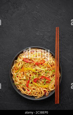 Nouilles Hakka à l'ail de piment dans un bol noir sur un dessus en tabpe d'ardoise sombre. Indo-chinois plat végétarien. Nouilles à légumes indiennes. Classique A. Banque D'Images