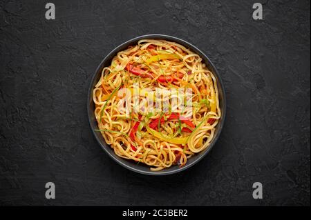 Nouilles Hakka à l'ail de piment dans un bol noir sur un dessus en tabpe d'ardoise sombre. Indo-chinois plat végétarien. Nouilles à légumes indiennes. Classique A. Banque D'Images