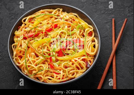 Nouilles Hakka à l'ail de piment dans un bol noir sur un dessus en tabpe d'ardoise sombre. Indo-chinois plat végétarien. Nouilles à légumes indiennes. Classique A. Banque D'Images