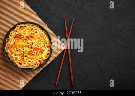 Nouilles Hakka à l'ail de piment dans un bol noir sur un dessus en tabpe d'ardoise sombre. Indo-chinois plat végétarien. Nouilles à légumes indiennes. Classique A. Banque D'Images