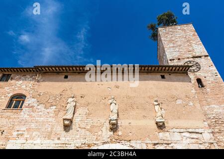 La porte consulaire romaine, avec la tour et l'horloge. Un des accès aux remparts de la ville. Trois statues au-dessus de l'arche. En Spello, province de per Banque D'Images