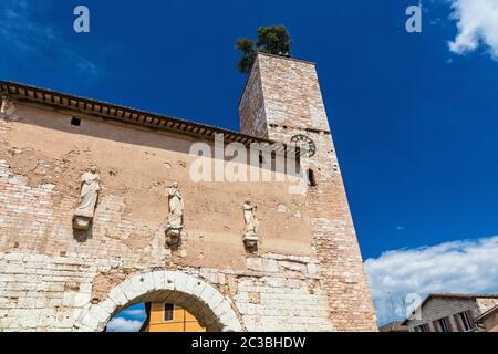 La porte consulaire romaine, avec la tour et l'horloge. Un des accès aux remparts de la ville. Trois statues au-dessus de l'arche. En Spello, province de per Banque D'Images