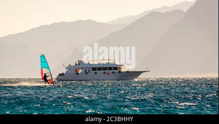 Grand bateau et planche à voile sur le fond des hautes montagnes en Egypte Dahab Sud Sinaï Banque D'Images